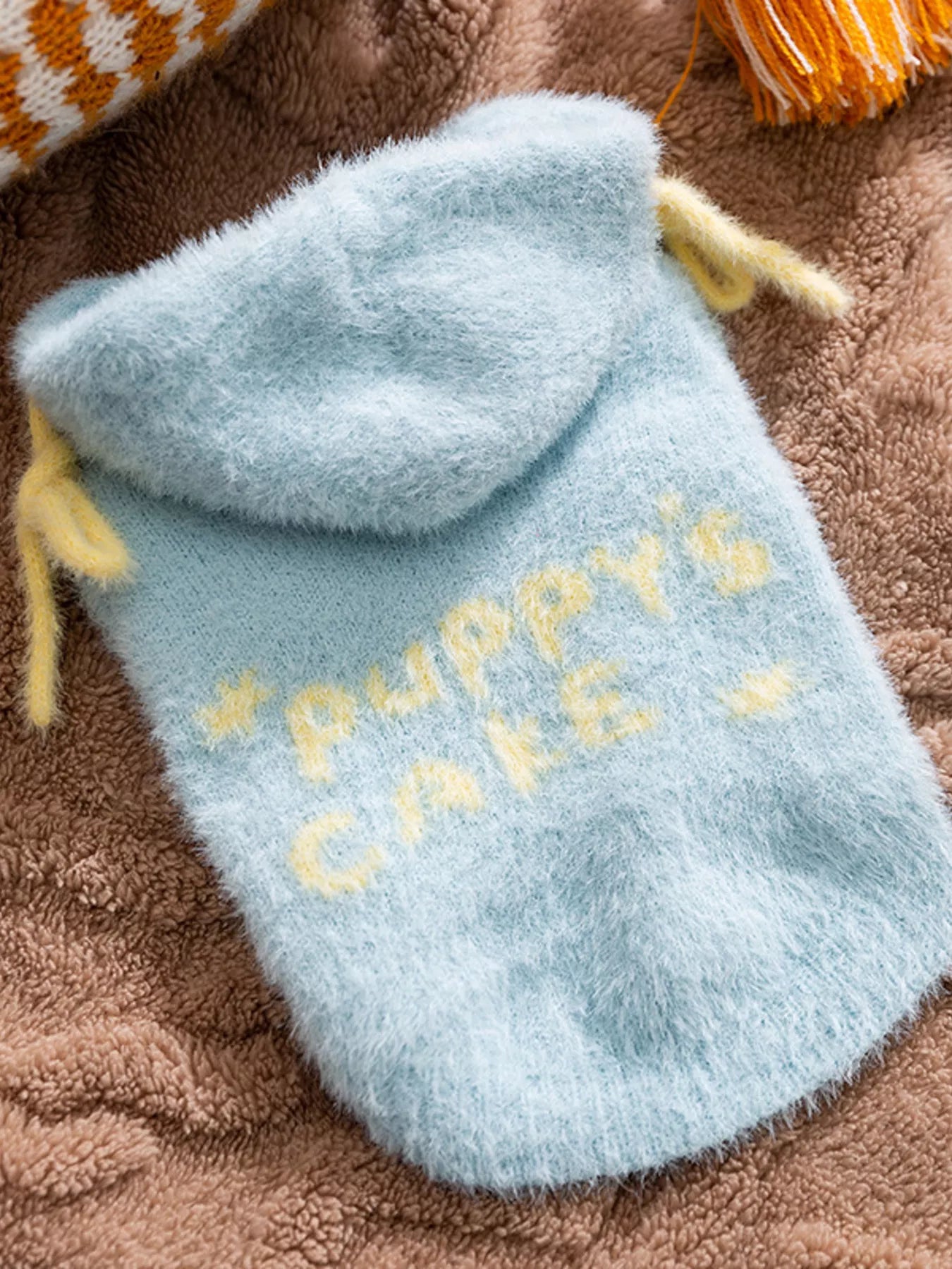 Blue plush toy with 'Puppy's Cake' text on a brown textured surface
