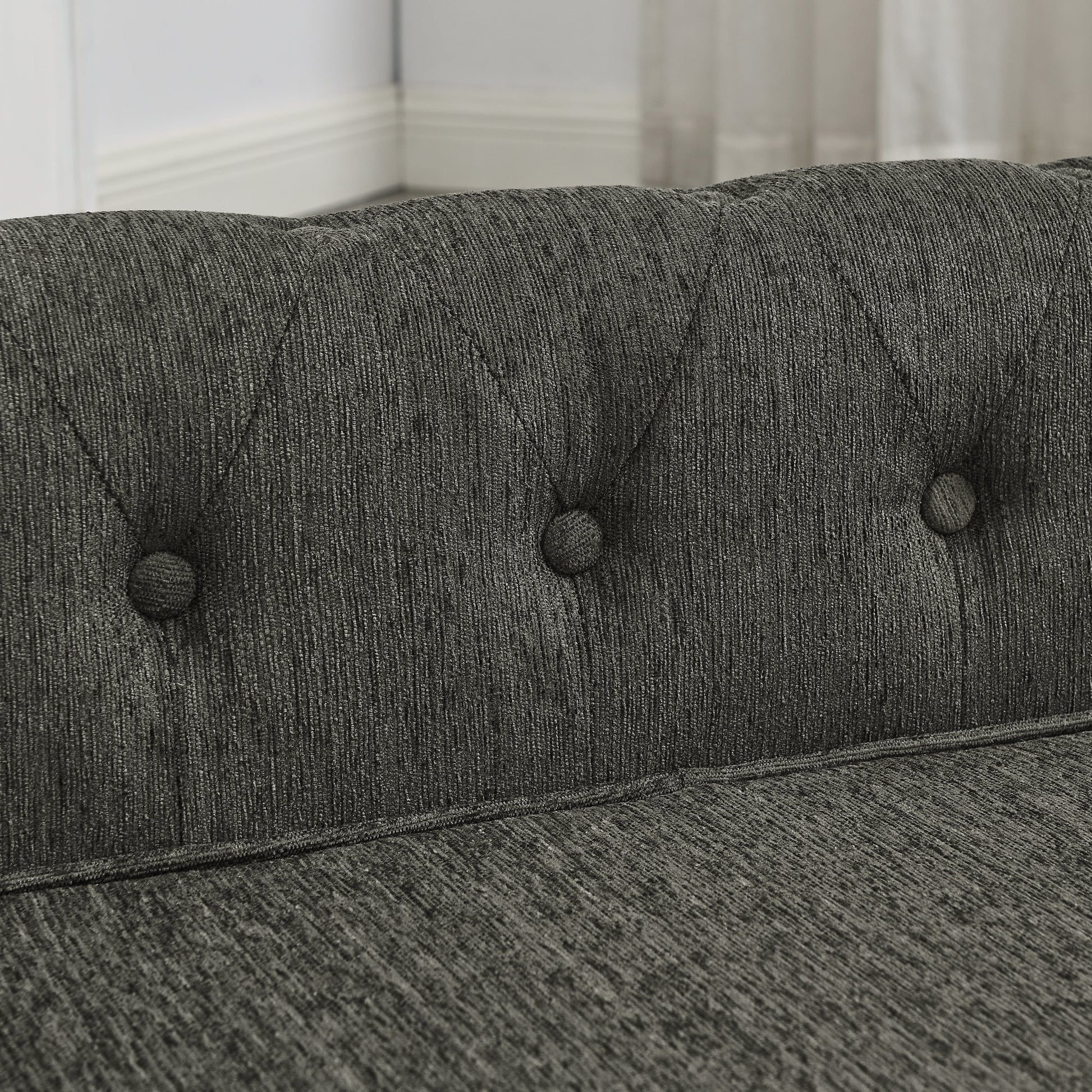 Close-up of a gray upholstered headboard with tufted buttons.