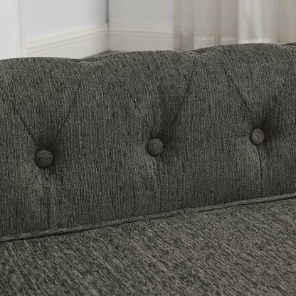 Close-up of a gray upholstered headboard with tufted buttons.