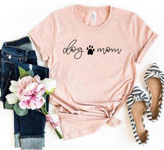 Pink t-shirt with 'dog mom' text, jeans, flowers, and shoes on a white background
