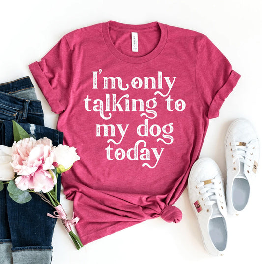 Pink t-shirt with 'I'm only talking to my dog today' text, paired with jeans and sneakers on a white background