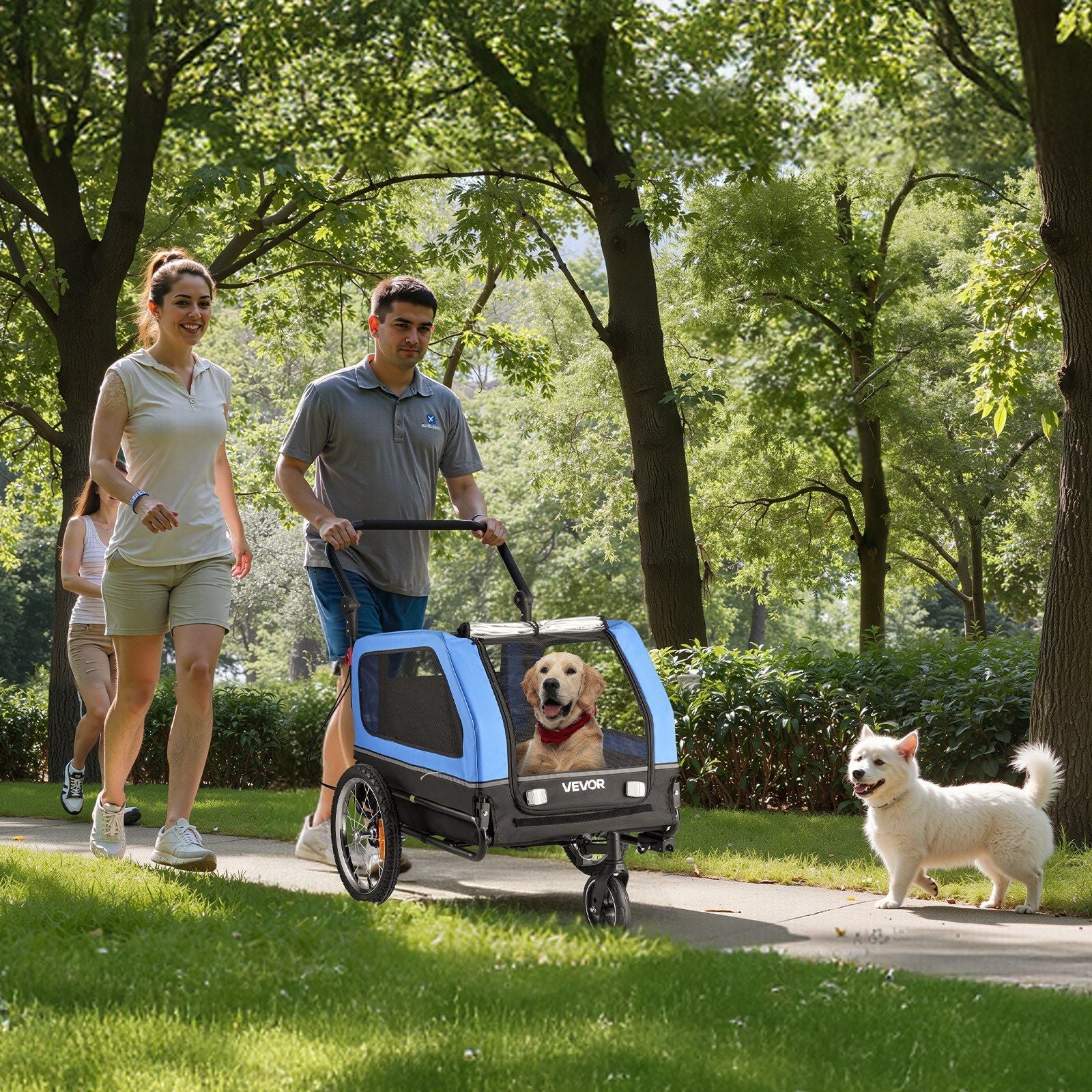 Two people walking with a dog in a trailer in a park
