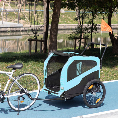 Bicycle with a blue and black trailer attached, parked on a path near a park.