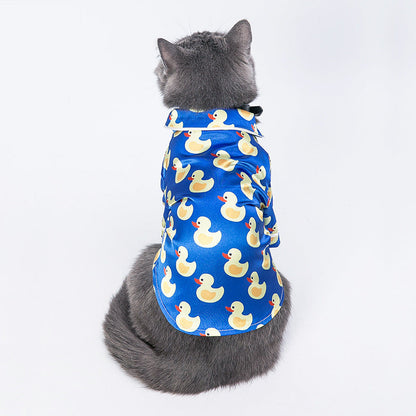 Cat wearing a blue shirt with yellow duck patterns on a white background