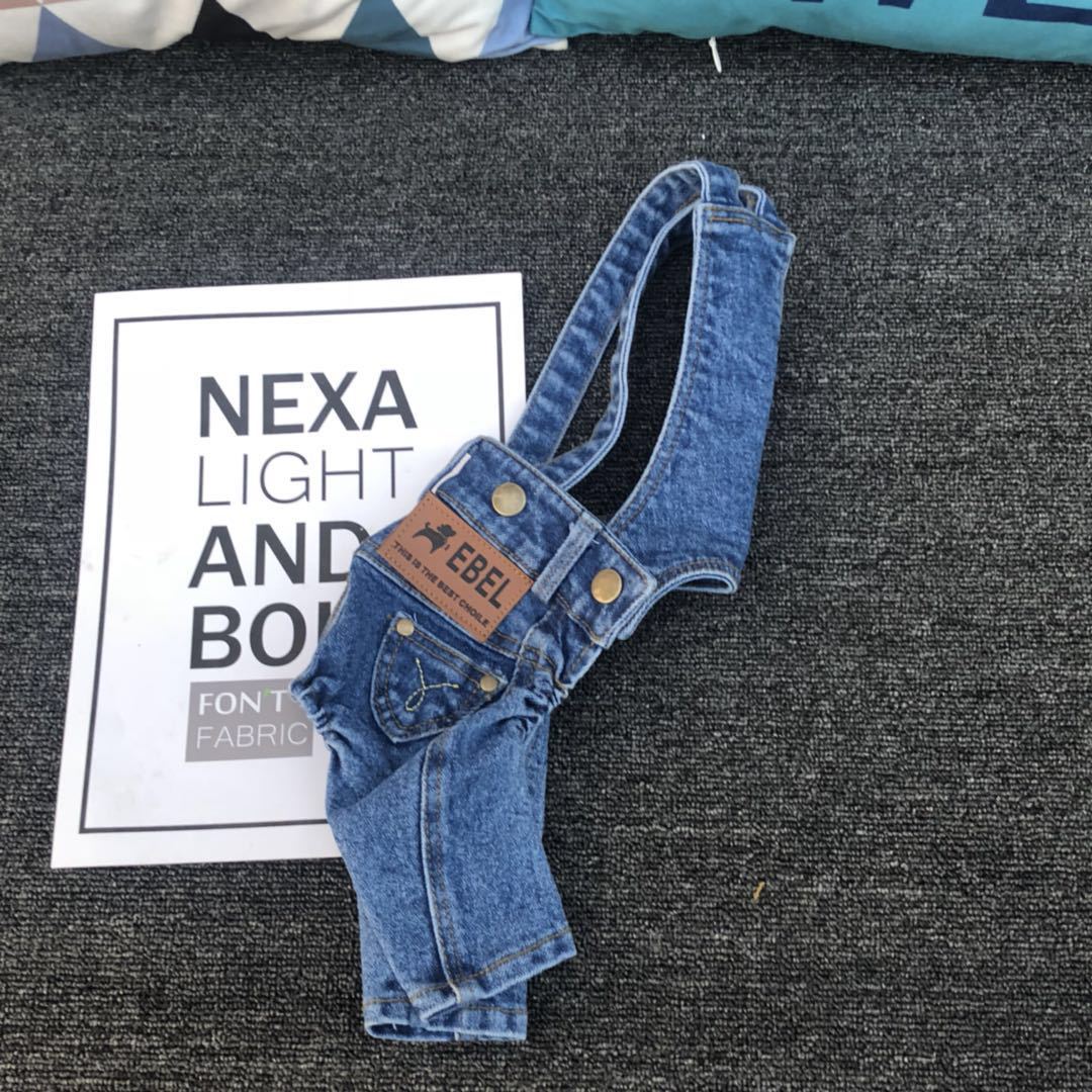 Blue denim overalls with a brand label on a dark textured surface.