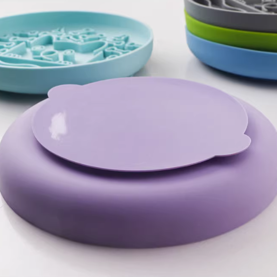 Purple silicone lid on a white surface with other silicone lids in the background.