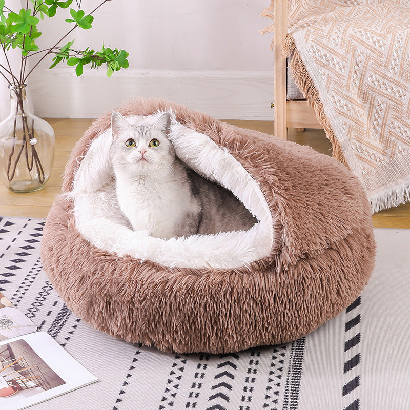 Cat sitting in a plush, brown pet bed on a patterned rug.