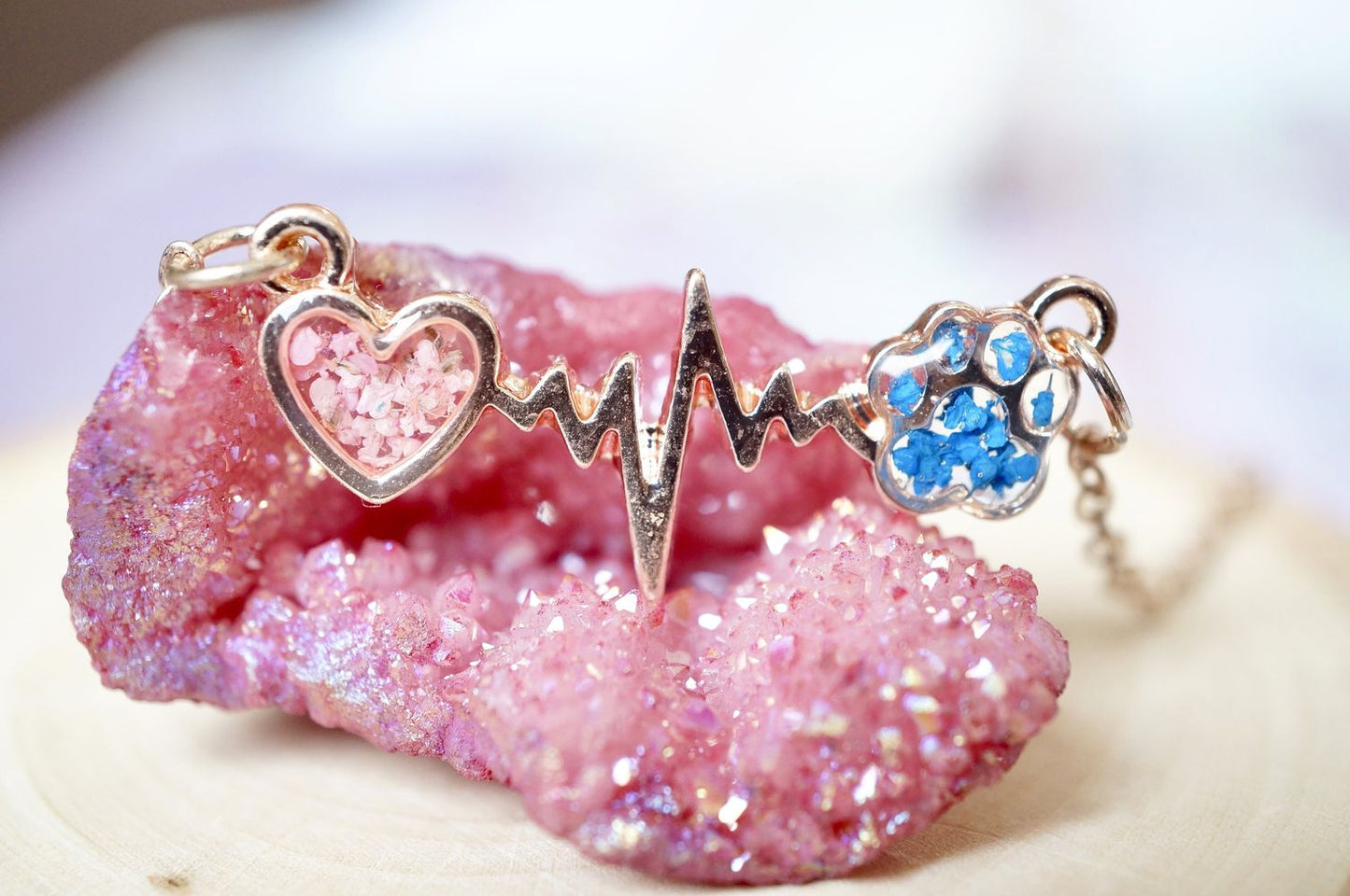 Necklace with heart, heartbeat, and paw design on a pink crystal background