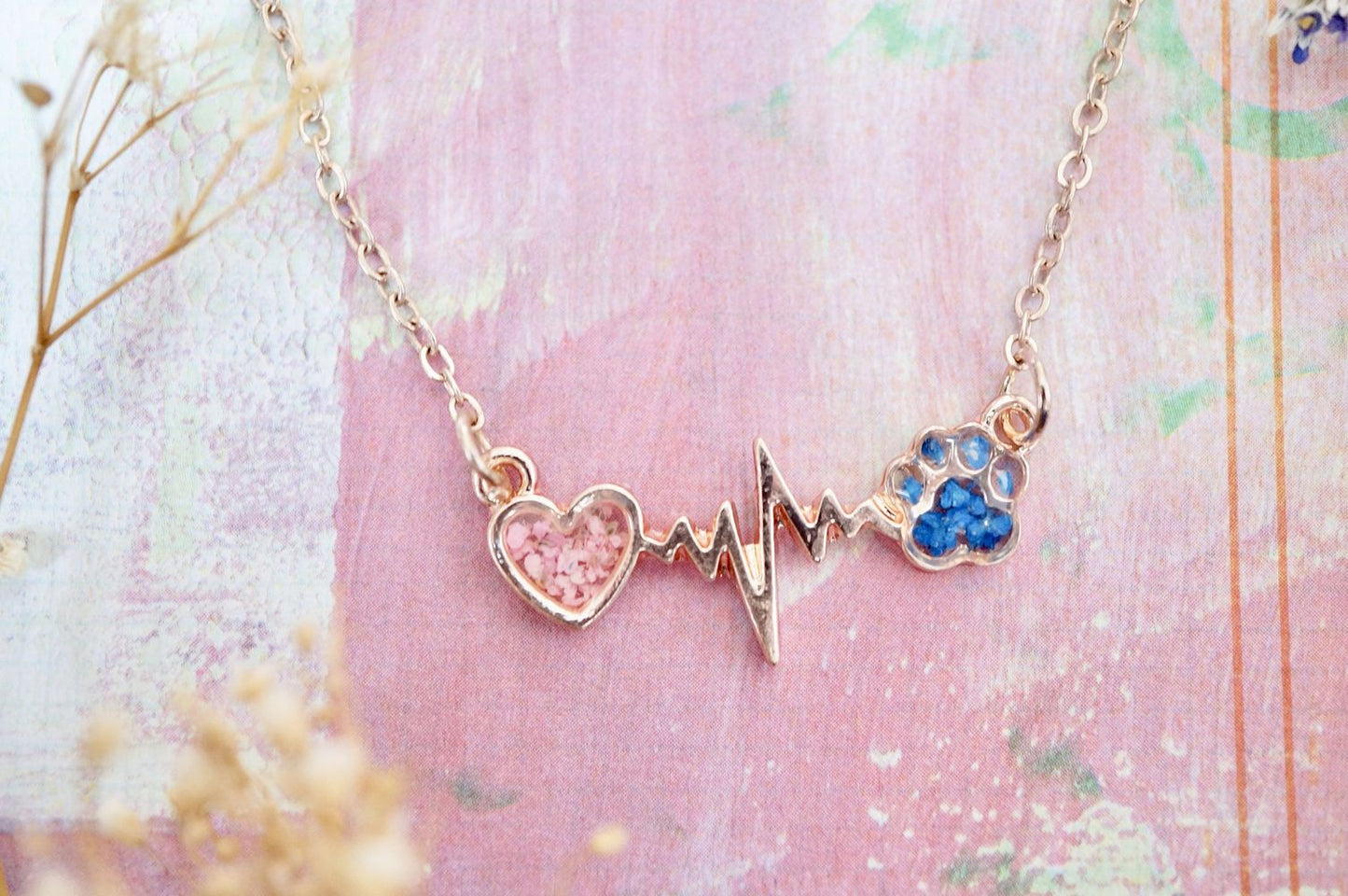 Necklace with heart and paw print design on a pink background