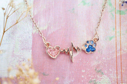 Necklace with heart and paw print design on a pink background