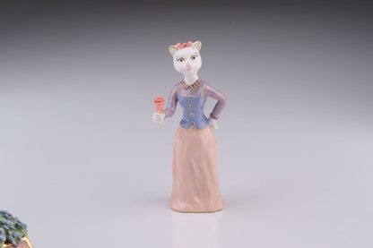 Cat figurine in a dress holding a flower on a gray background