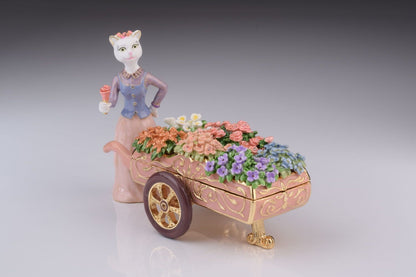 Decorative box with a cat figure pushing a cart of flowers on a gray background