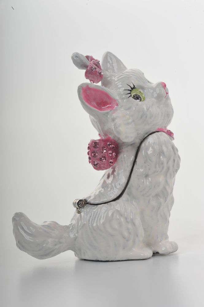 White ceramic cat figurine with pink embellishments on a white background