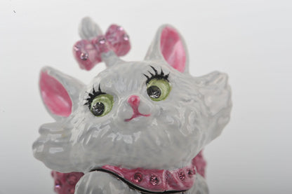 Decorative cat figurine with pink bow and green eyes on a white background