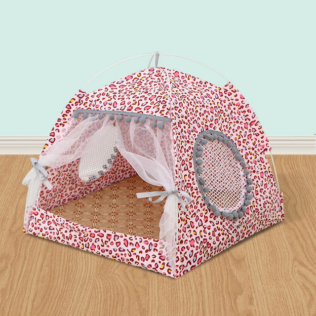 Pink pet tent with leopard print design on a wooden floor.