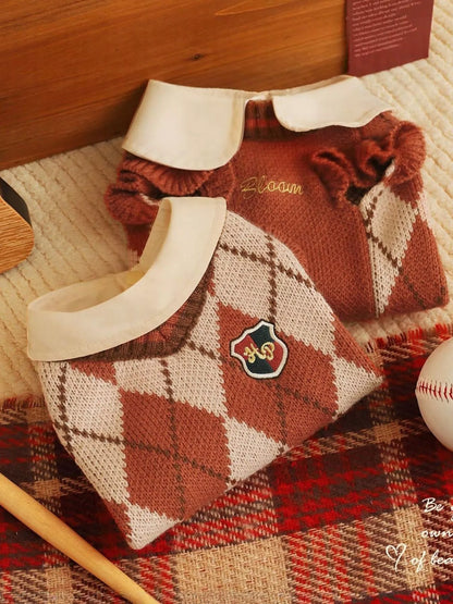 Plaid-patterned dog sweater with a collar on a textured surface