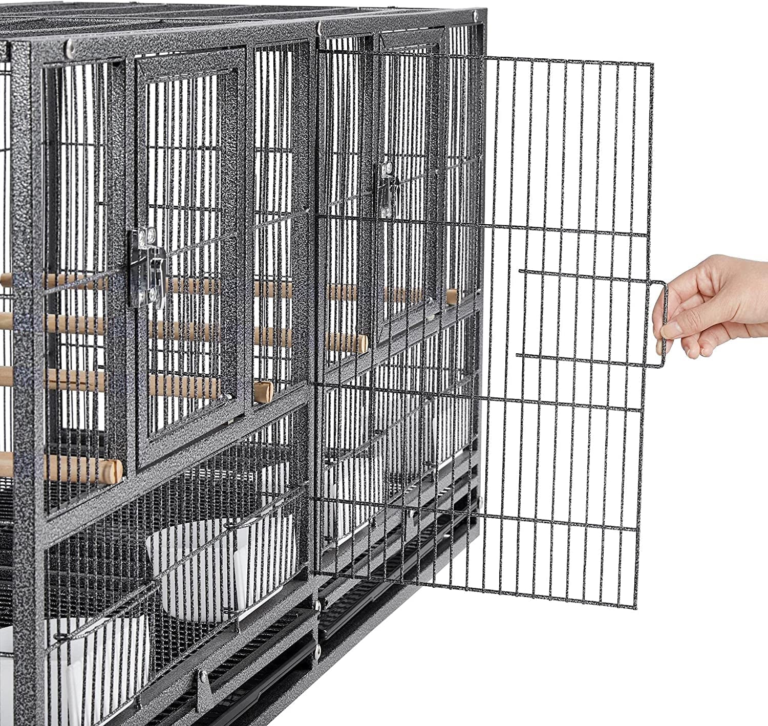 Large metal bird cage with a hand opening one of the doors on a white background