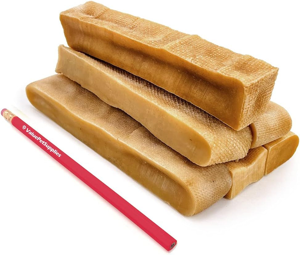 Stack of brown dog chew treats with a red pencil for scale on a white background