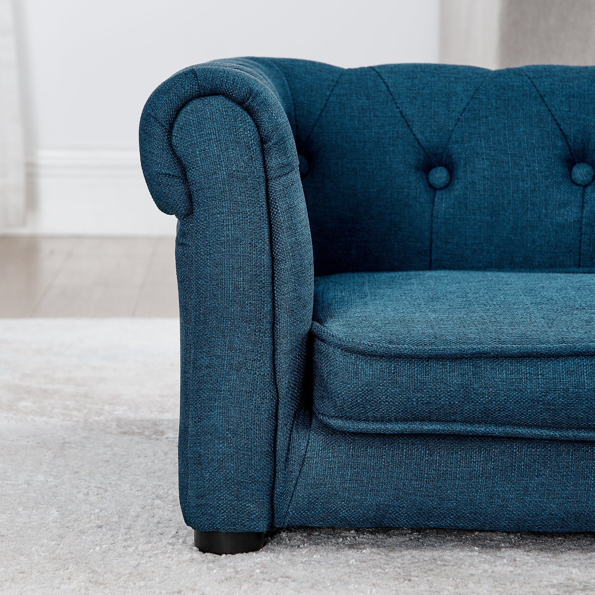 Blue upholstered chair with tufted backrest on a light gray carpet