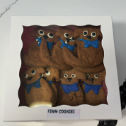 Four small owl figurines with blue bows in a decorative box