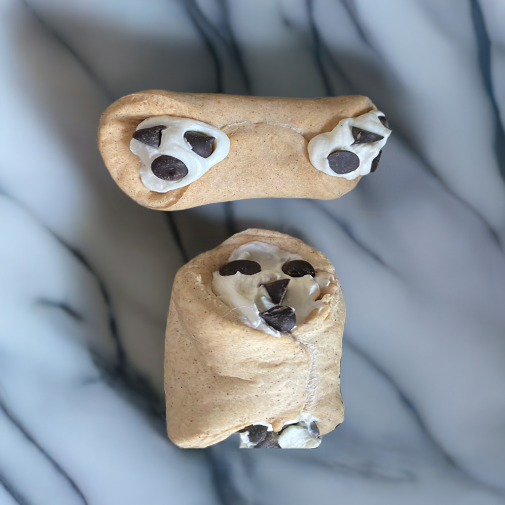 Two cookie-shaped dog treats with chocolate chips on a marble surface