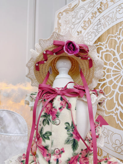 Decorative mannequin wearing a floral dress and pink ribbons with a decorative hat in the background.