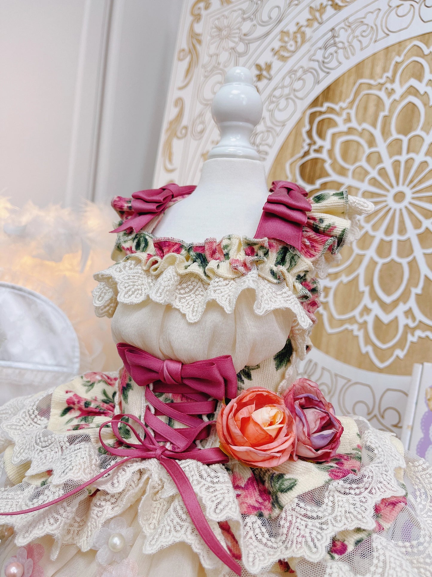 Mannequin wearing a floral dress with pink ribbons against a decorative background