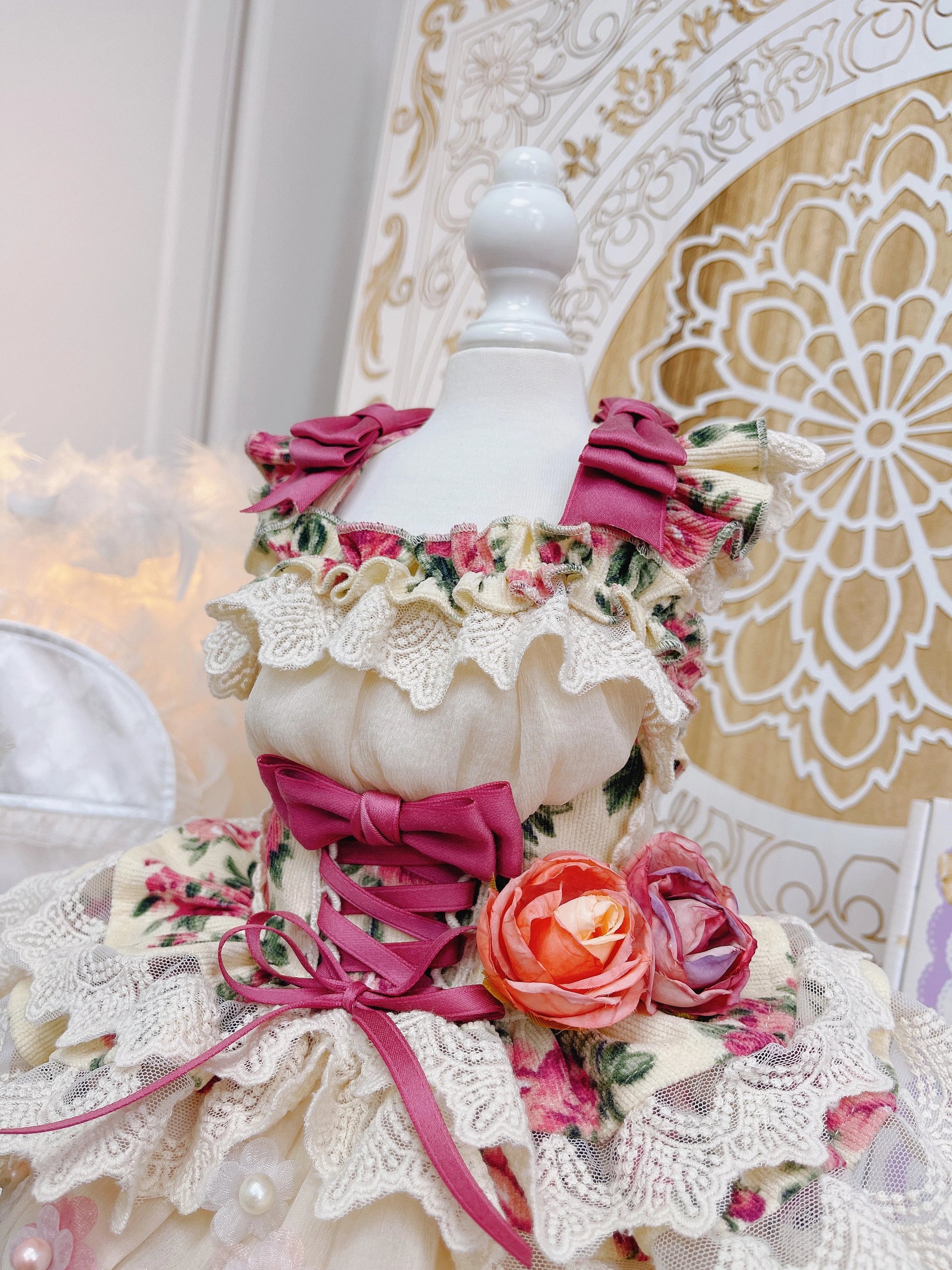 Mannequin wearing a floral dress with pink ribbons against a decorative background