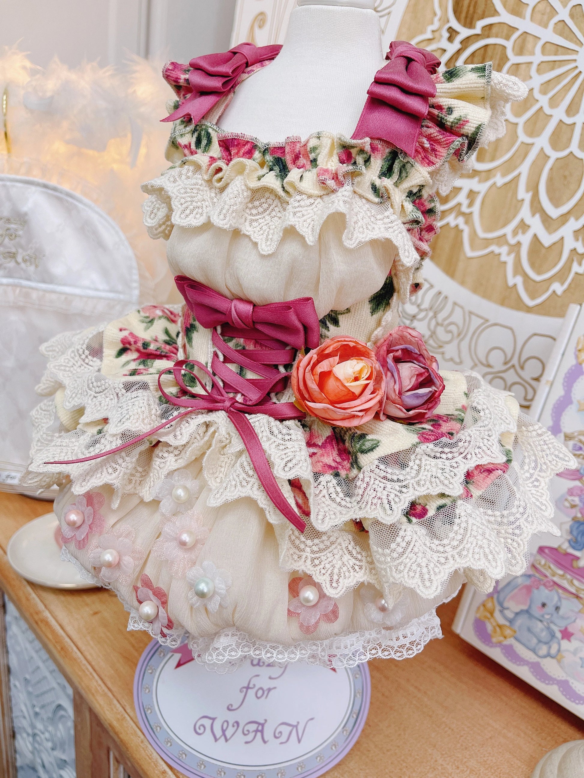 Decorative headpiece with flowers and ribbons on a mannequin head, set against a decorative background.