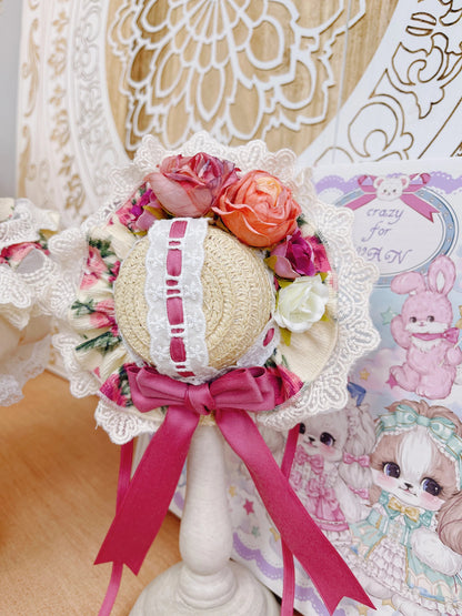 Decorative hat with flowers and a pink ribbon on a stand, with a patterned background