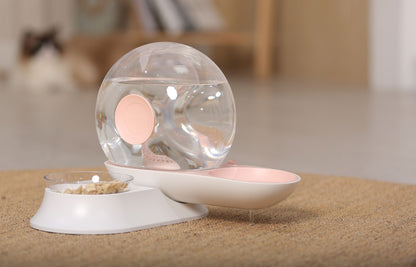 Pet water fountain with transparent sphere and pink base on a wooden surface