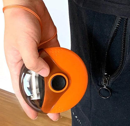 Person holding a small orange device with a lens, possibly a lens cleaning tool, against a neutral background.