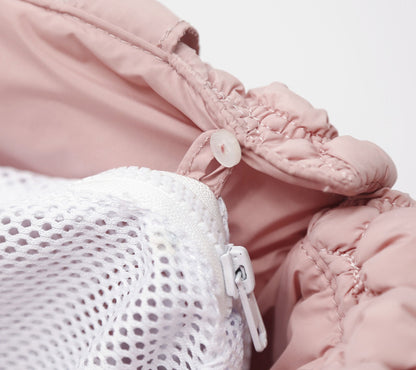 Close-up of pink baby pants with a white mesh bag underneath on a light background