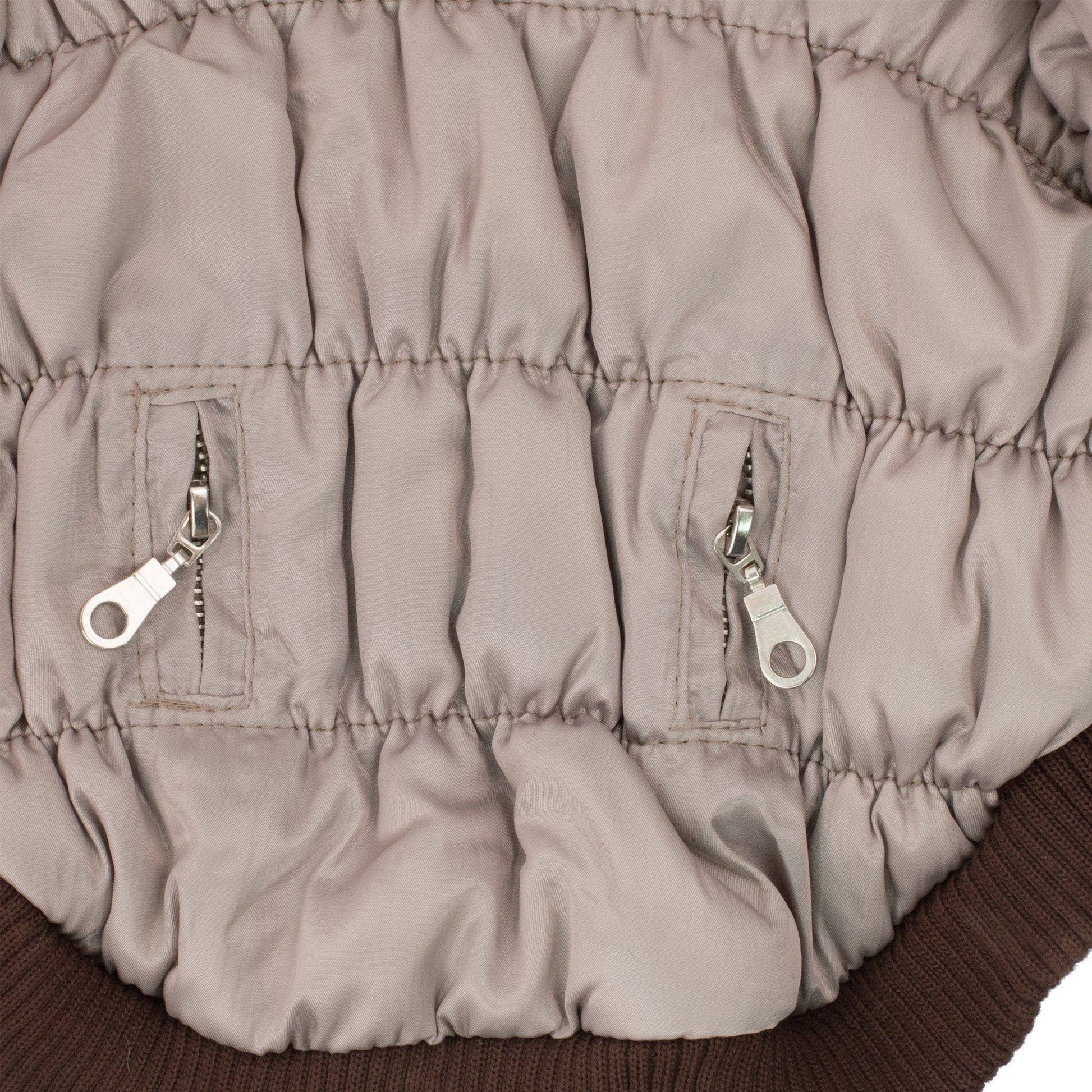 Close-up of a beige puffer jacket with zippers on a brown background