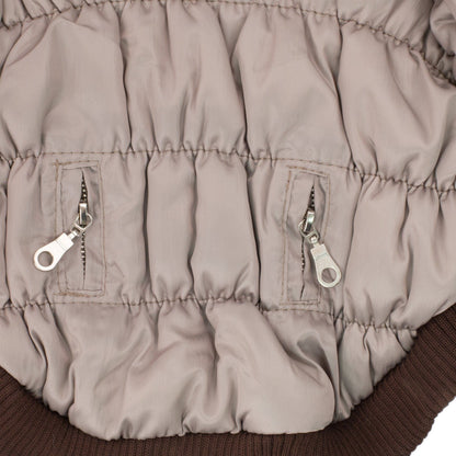 Close-up of a beige puffer jacket with zippers on a brown background