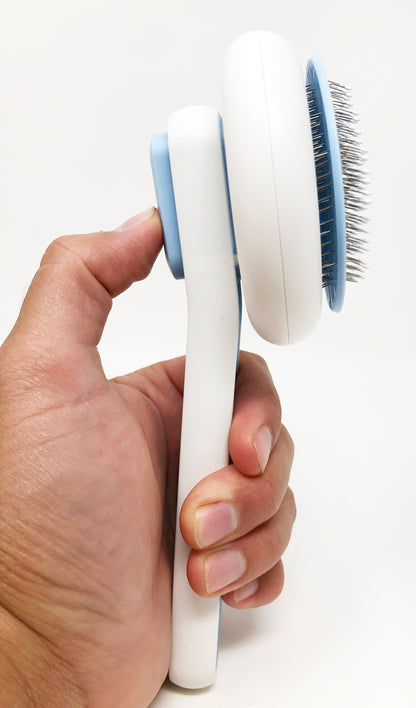 Hand holding a white and blue grooming brush on a white background