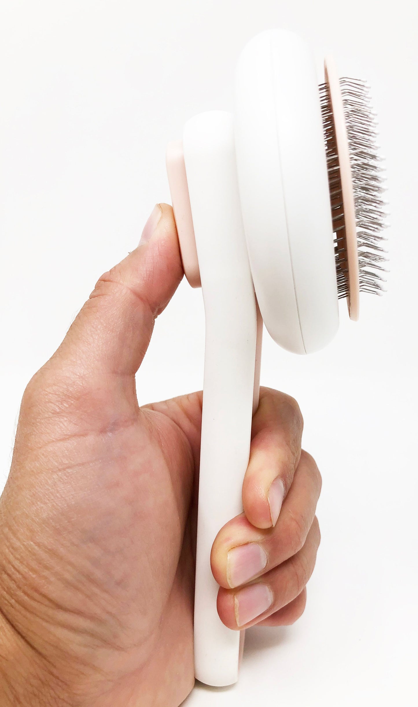 Hand holding a white hairbrush with bristle head on a white background
