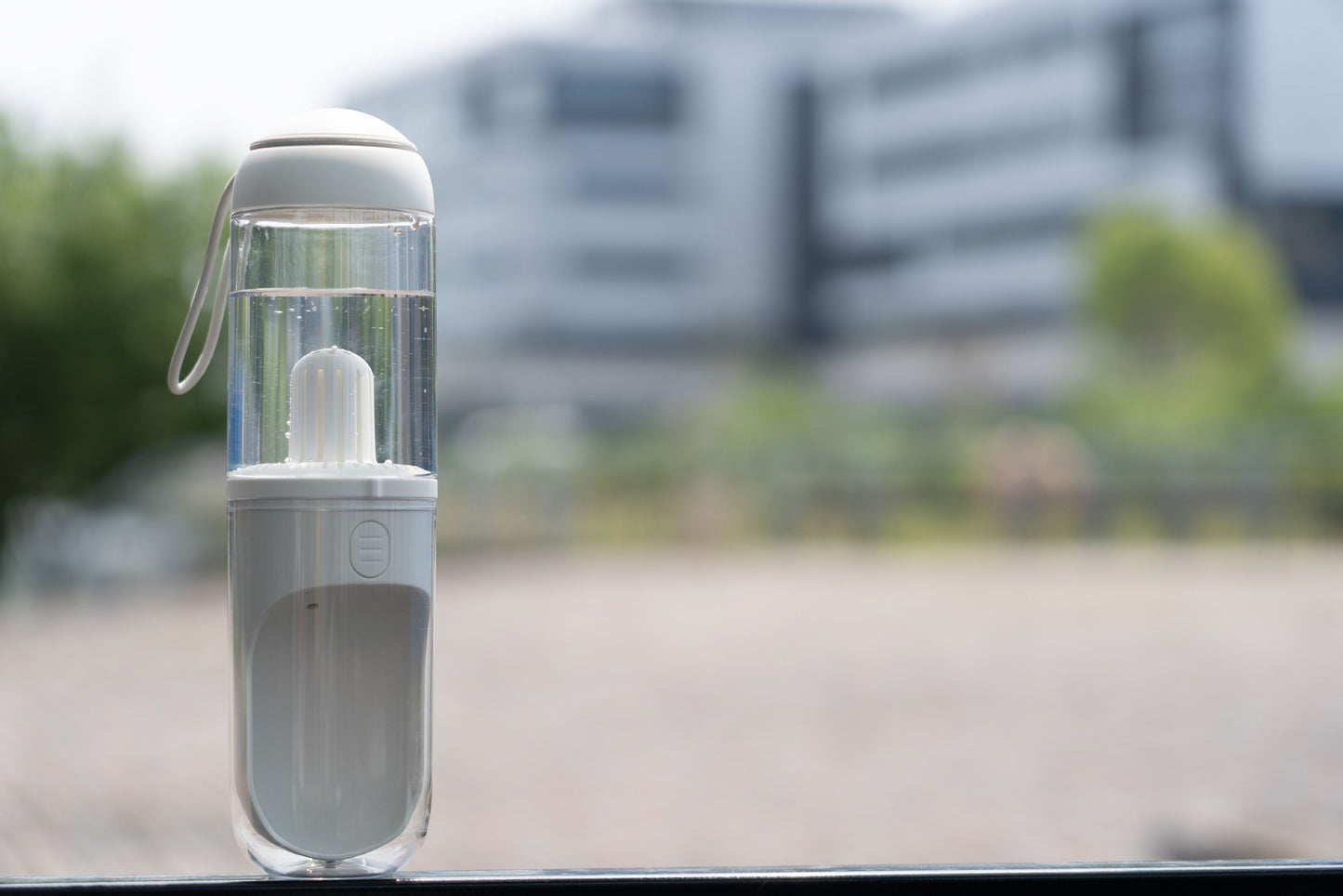 Clear water bottle with white cap on a blurred outdoor background