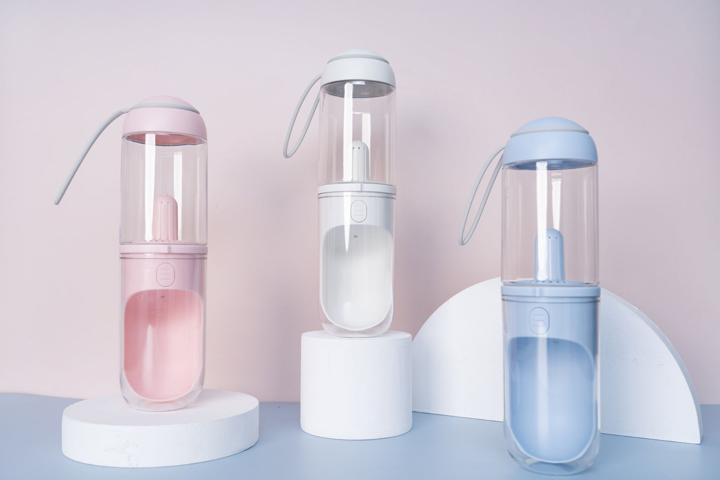 Three transparent bottles with colorful liquid on a light pink background