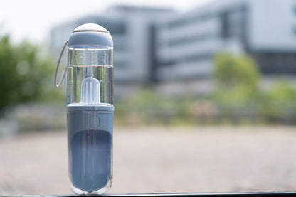 Clear spray bottle with a nozzle on a car window with a blurred outdoor background