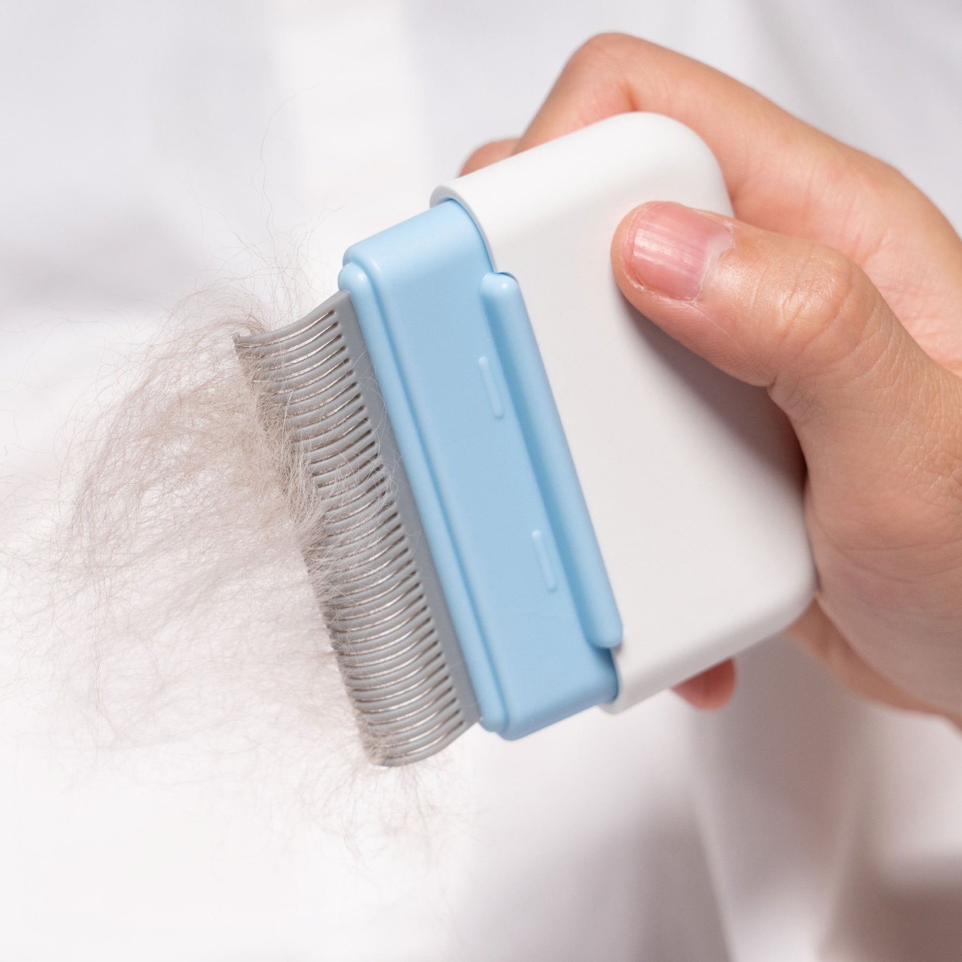 Hand using a pet grooming brush with a clear background