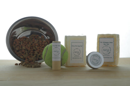 Collection of pet care products including a bowl, balls, and soap bars on a wooden surface.
