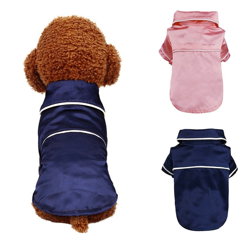 Dog wearing a navy blue raincoat with white trim, pink raincoat, and additional navy blue raincoat on a white background.