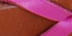 Close-up of pink ribbon on a brown background