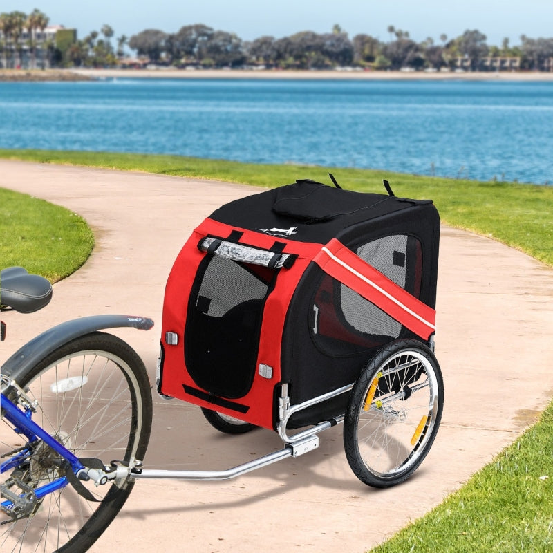 Red and black bicycle pet trailer attached to a bike by a lake.