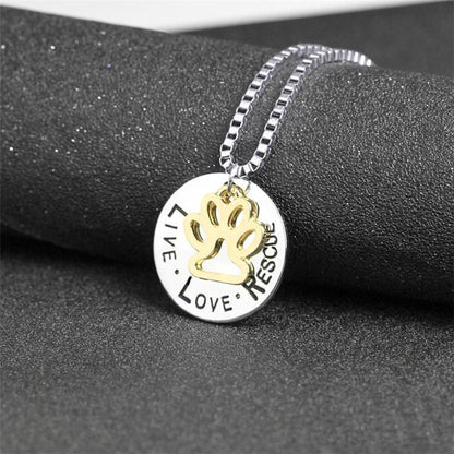 Necklace with a pendant featuring paw print and engraved text on a dark surface