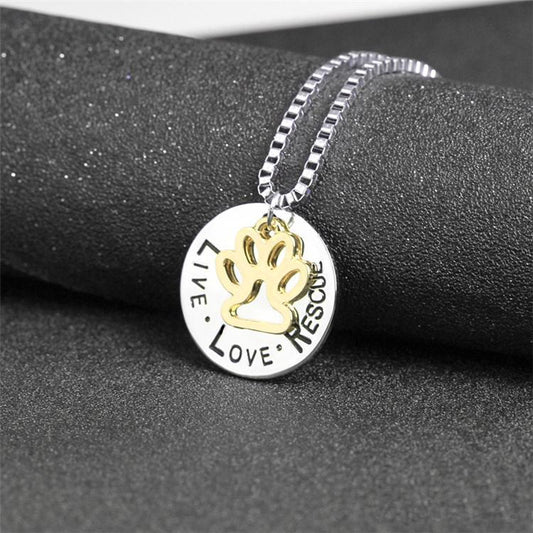 Necklace with a pendant featuring paw print and engraved text on a dark surface