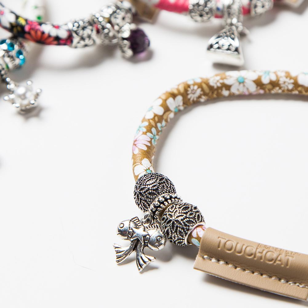 Bracelet with floral pattern and various charms on a white background