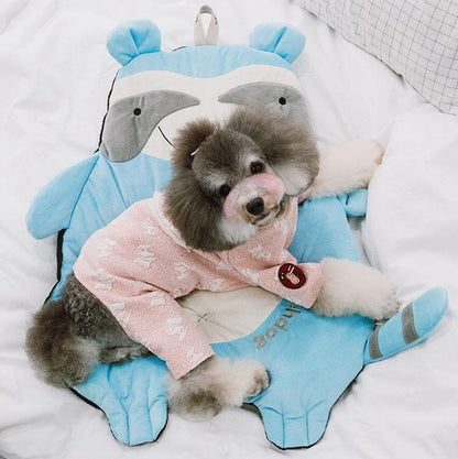 Small dog in a pink outfit lying on a blue animal-shaped pillow