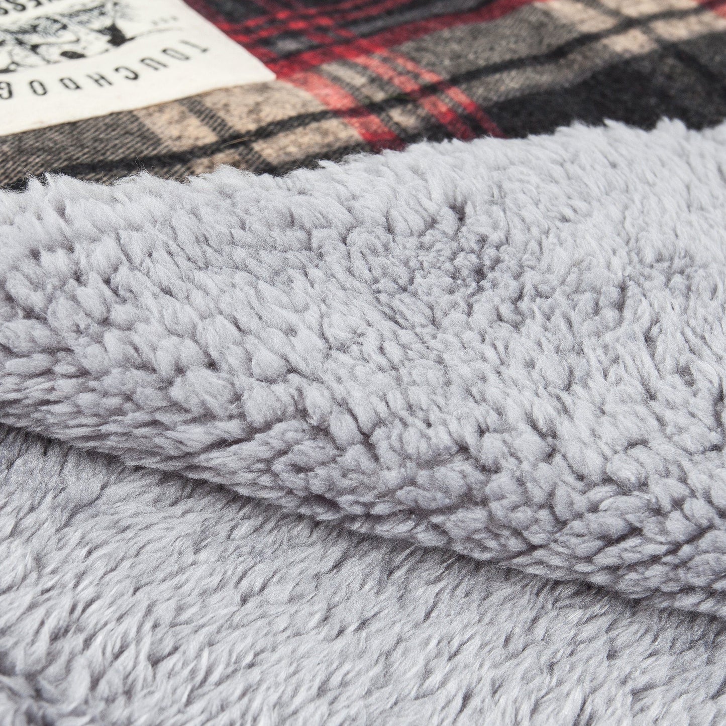 Close-up of a textured gray fabric with a plaid pattern in the background